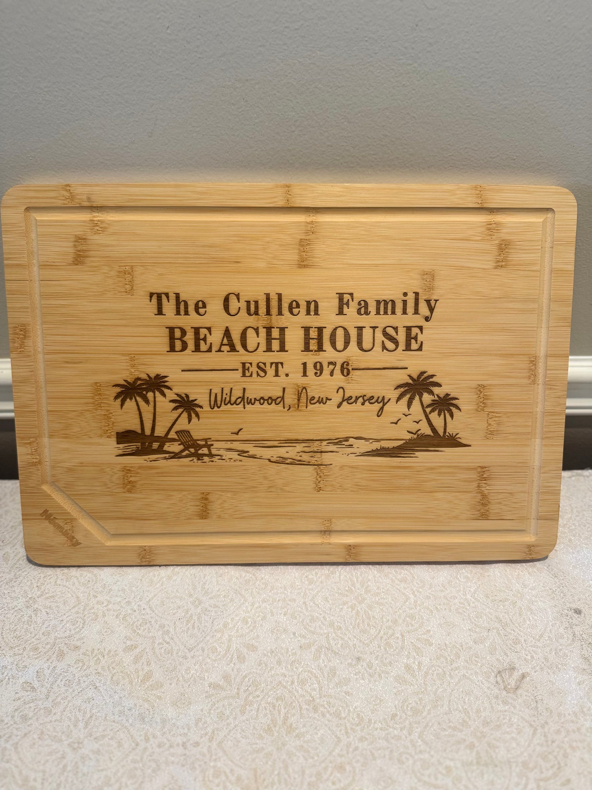 Bamboo cutting board with engraved text and beach scene design on a neutral background