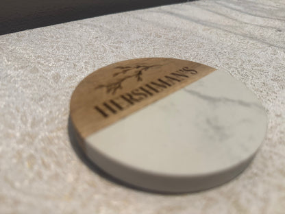 Round stone coaster with 'Hershimans' branding on a light stone surface