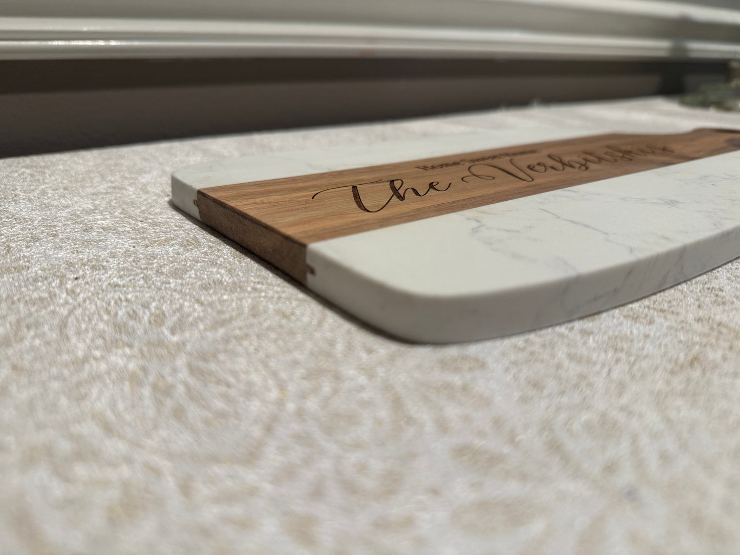 Wooden and marble cutting board with 'The Table' engraving on a marble surface.