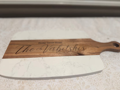 Personalized wooden cutting board with engraved text on a marble surface