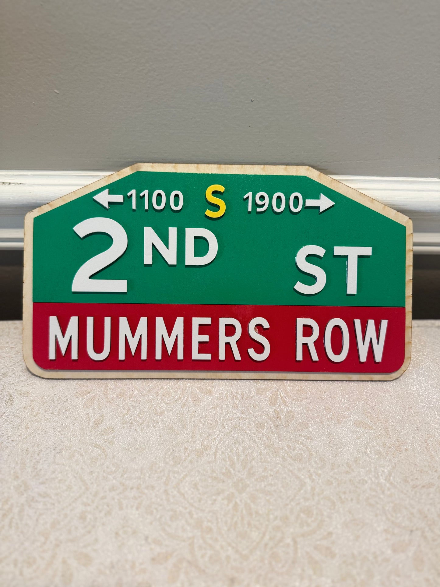 Street sign for 2nd St, Mummer's Row with directional arrows on a plain background