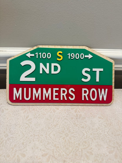 Street sign for 2nd St, Mummer's Row with directional arrows on a plain background