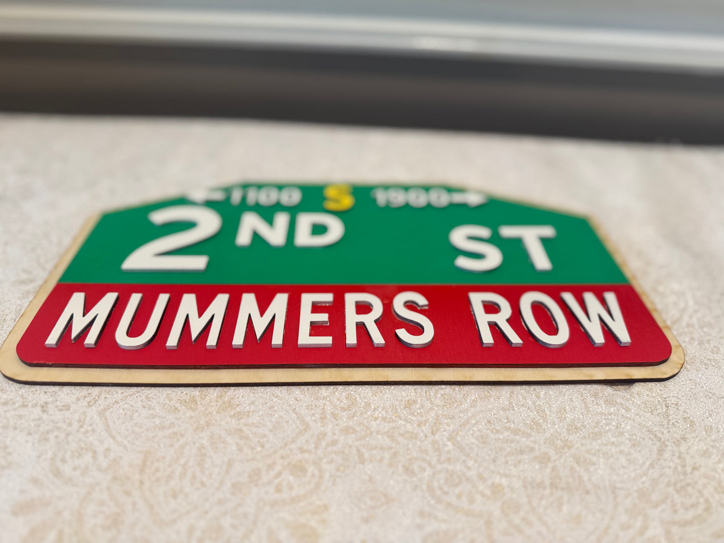 Street sign for '2nd St MUMMERS ROW' on a textured surface