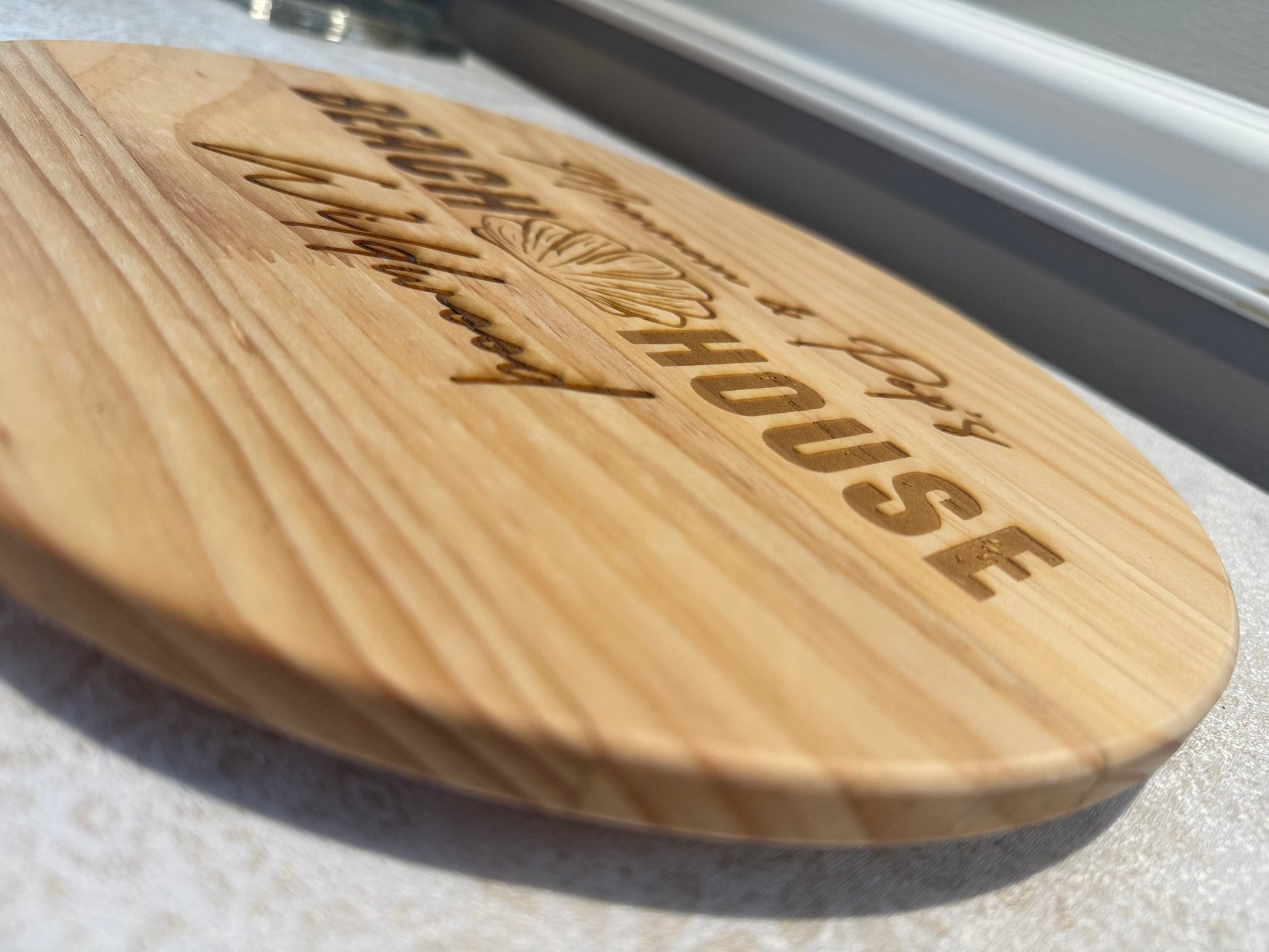 Wooden paddle board with 'Cayman Islands House' branding on a textured surface.