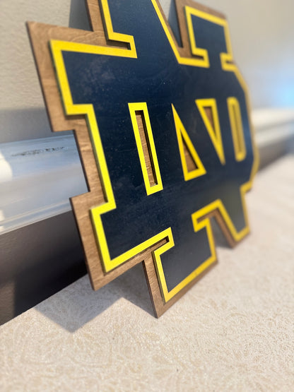 Decorative letter 'D' with gold border on a beige surface