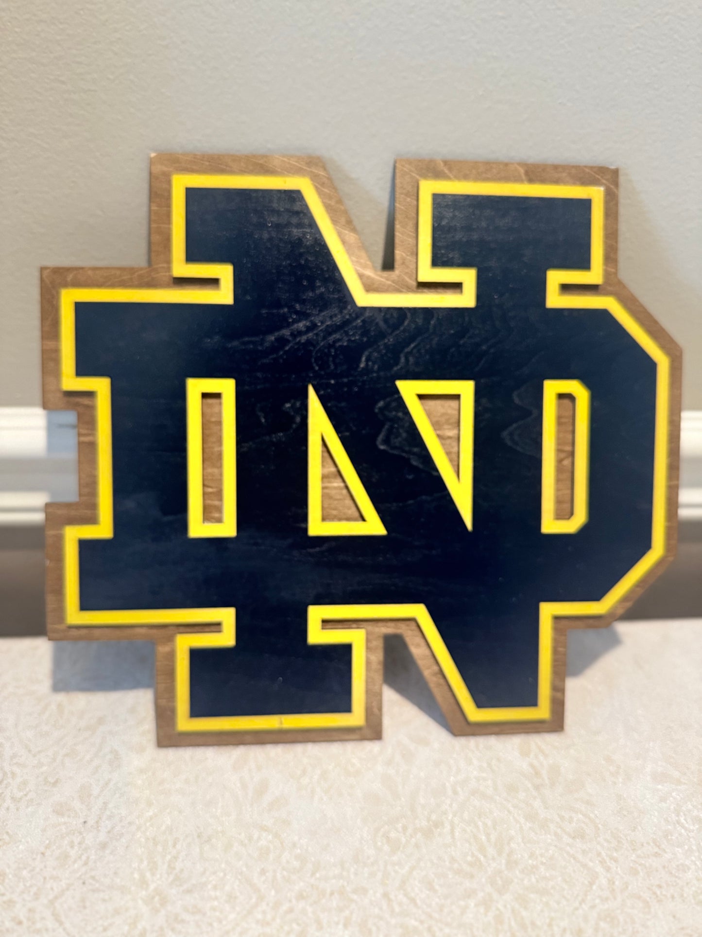 Wooden letter 'N' with blue background and yellow border on a light background
