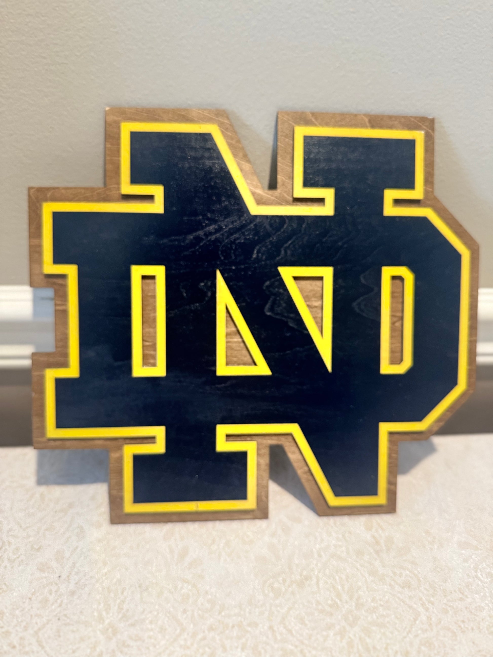 Wooden letter 'N' with blue background and yellow border on a light background