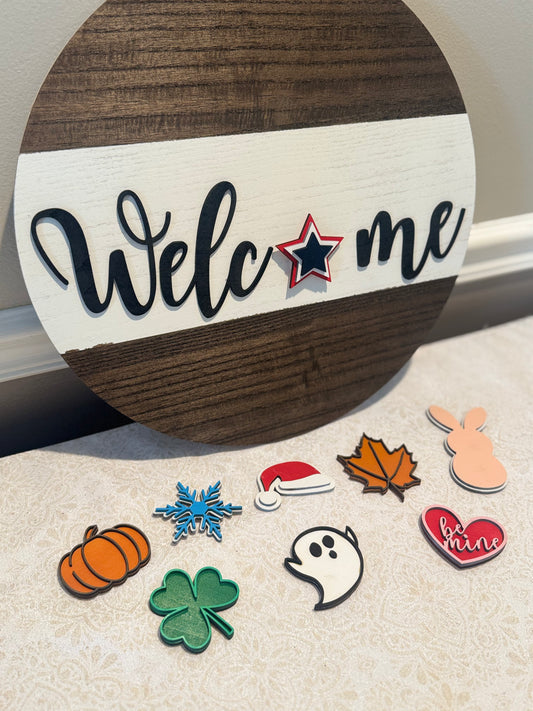 Round wooden sign with 'Welcome' text and decorative stickers on a light surface.