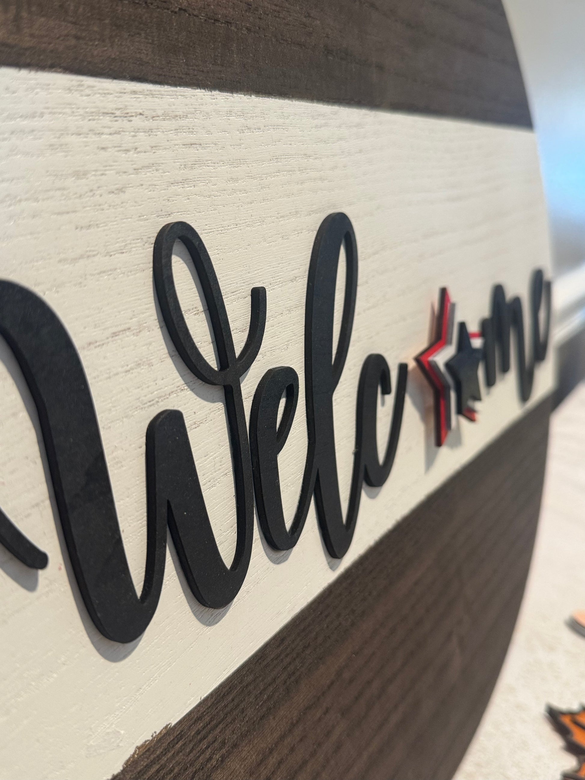 Wooden sign with 'Welcome' text and decorative elements on a blurred background