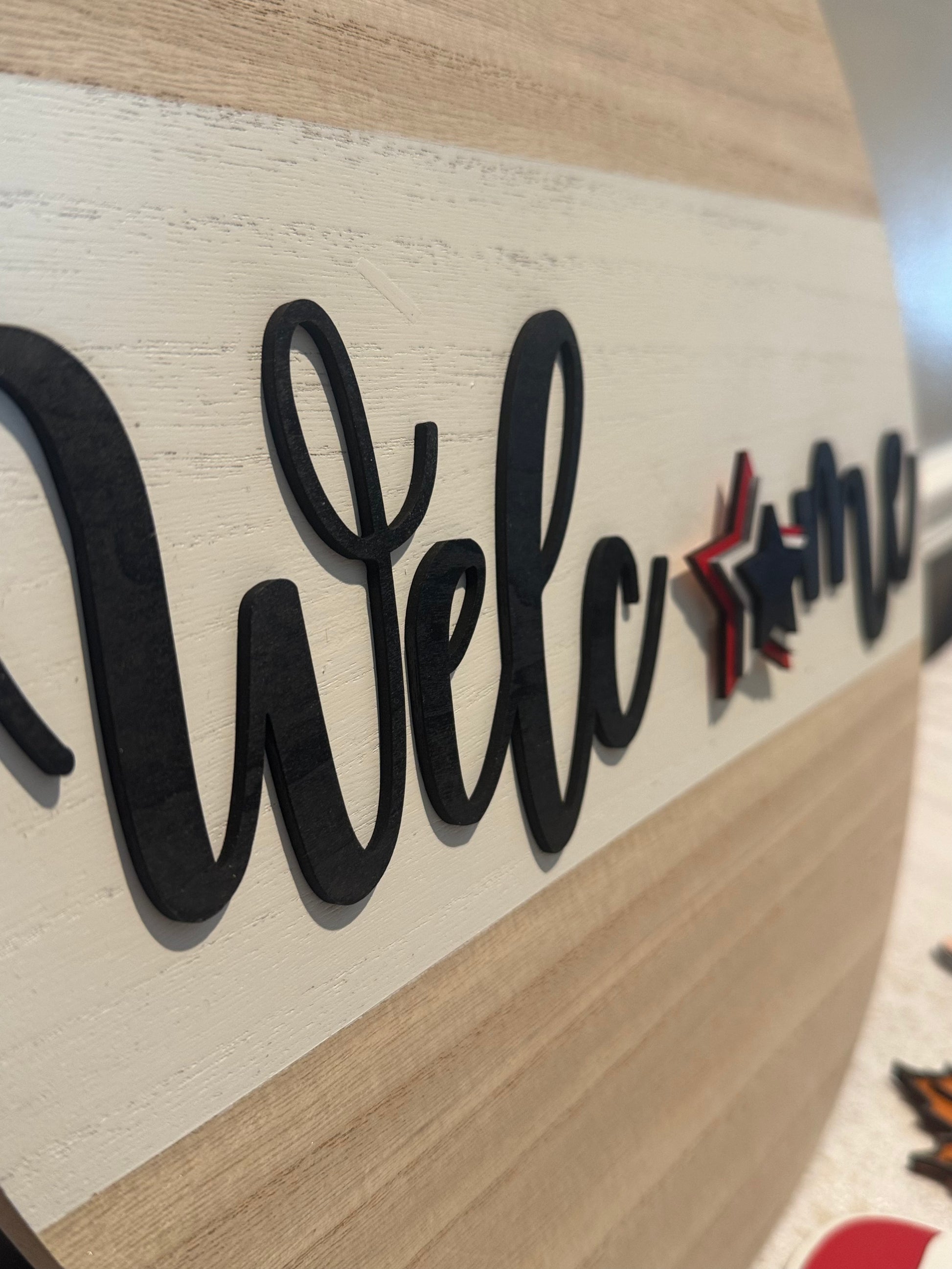 Wooden sign with 'Welcome' in black letters on a light wood background