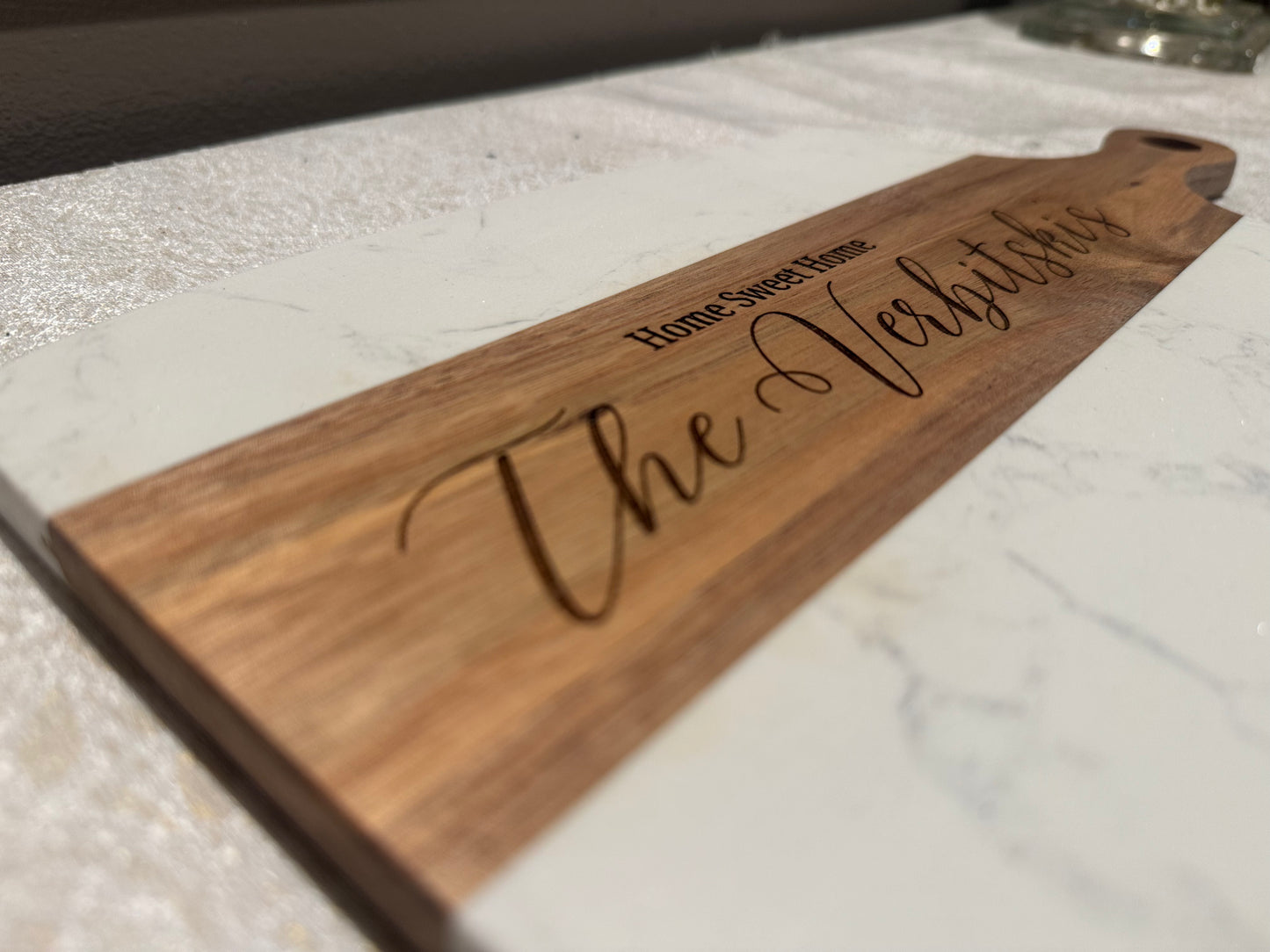 Wooden cutting board with engraved text on a marble surface